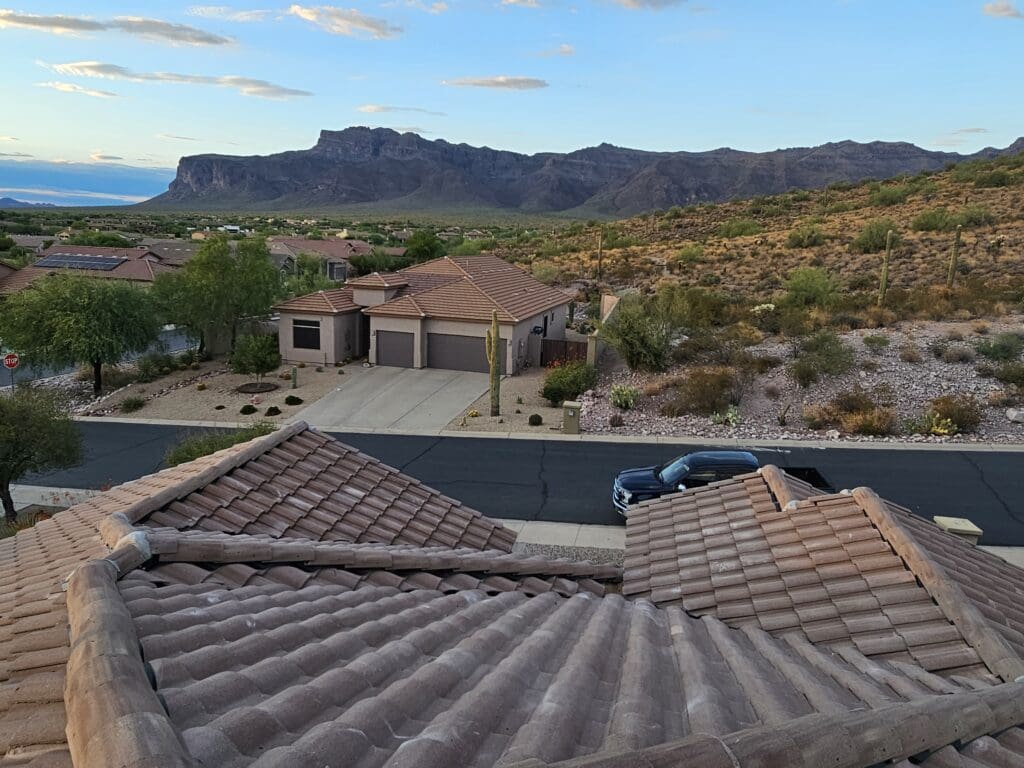 View of home in Arizona with catus and other dessert like foliage around and beautiful view of cliffs in the background.