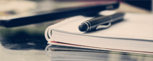 Close up view of a pen on top of a notebook on a table