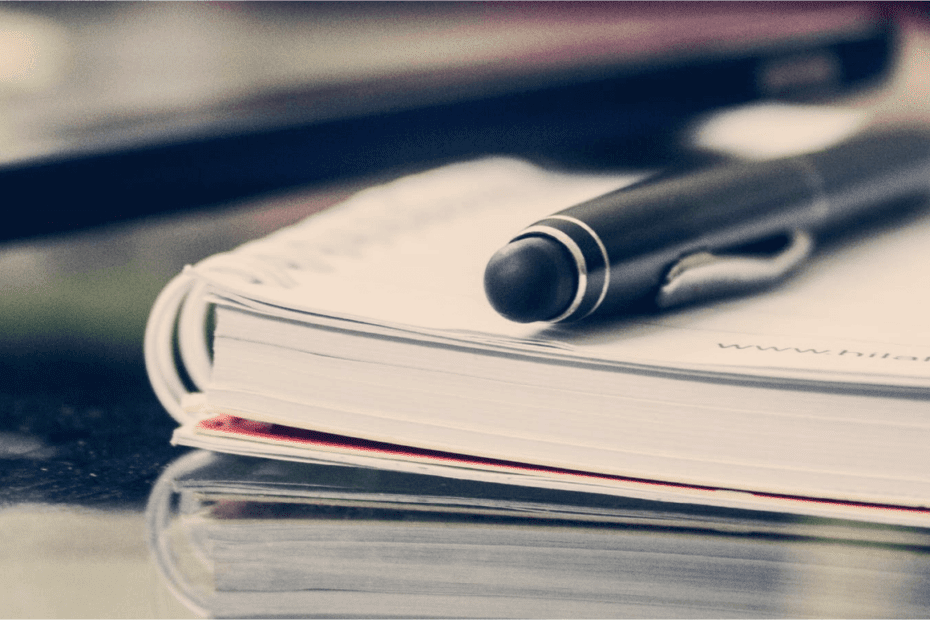 Close up view of a pen on top of a notebook on a table